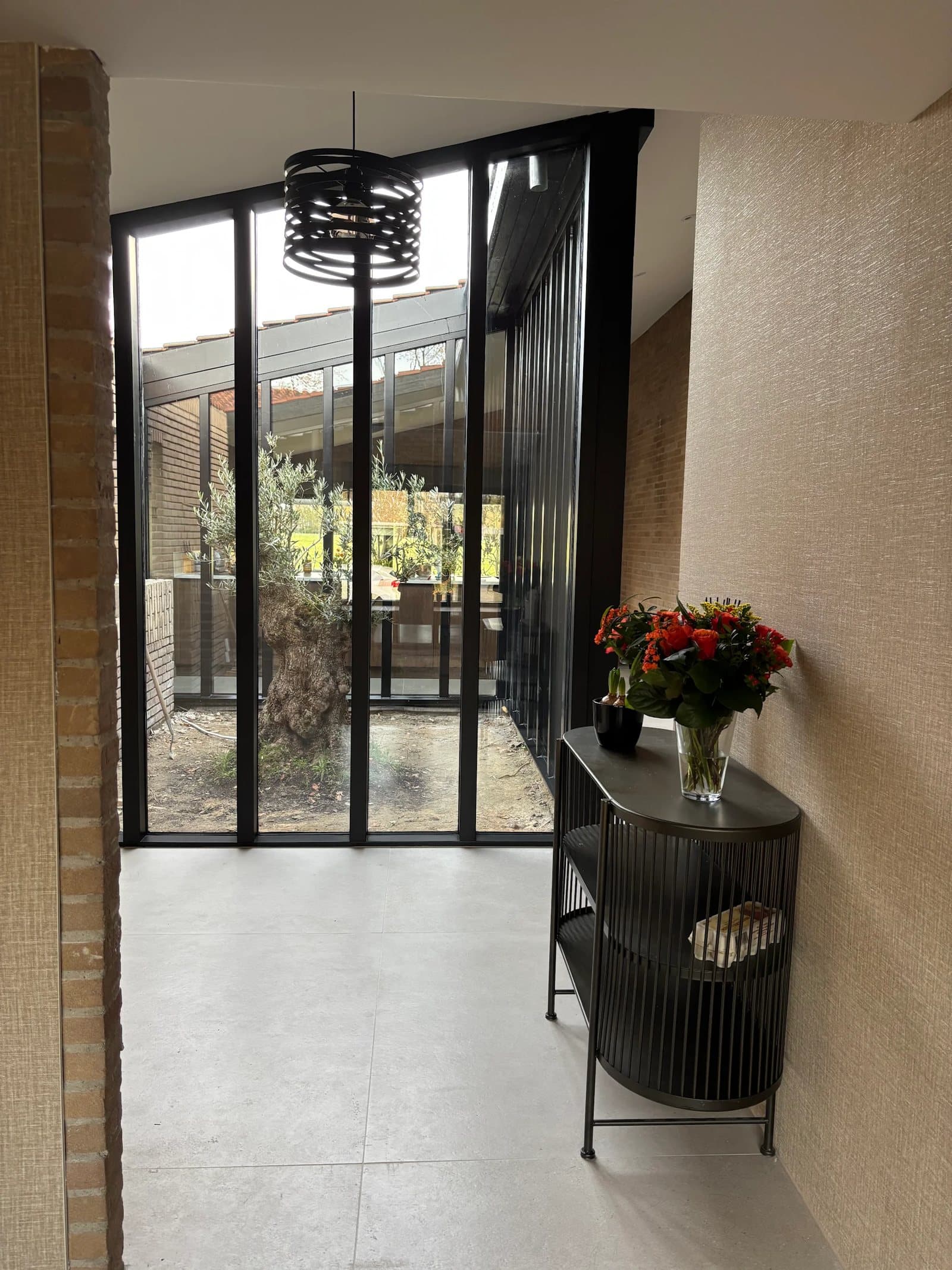 Glazen patio met door MTB Bouw zelf gemaakte zwarte kozijnen en een olijfboom in een Van Zantinge-villa