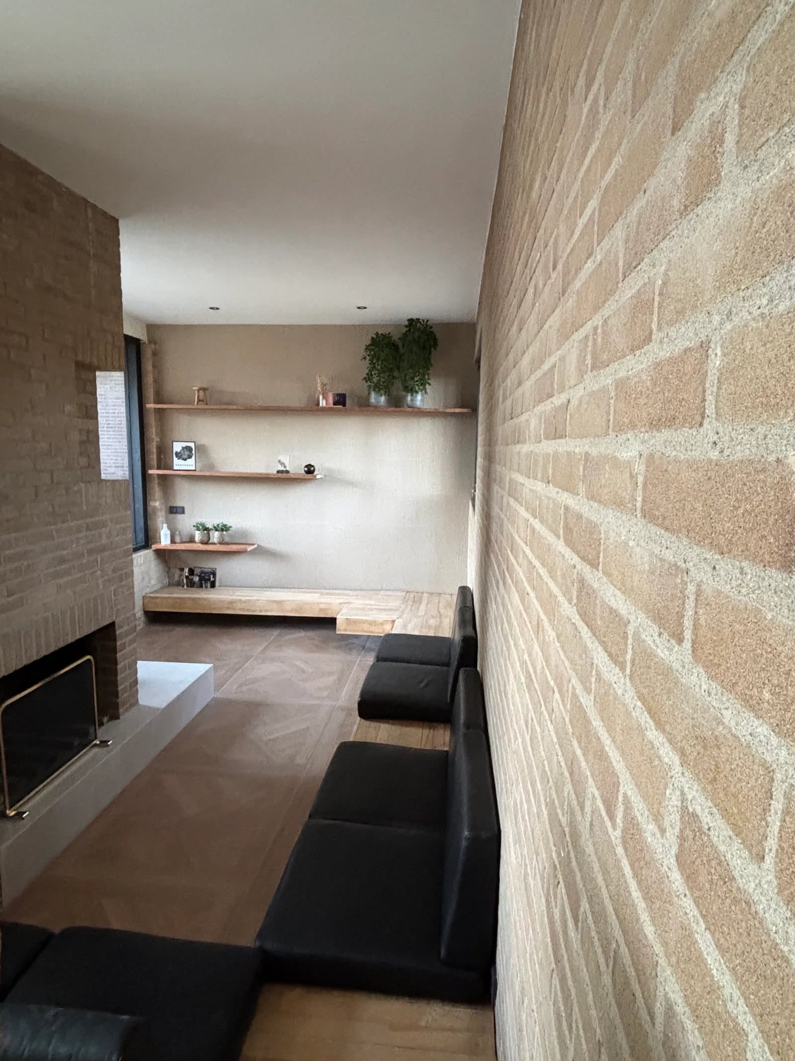 Zitkuil met maatwerk banken, haard, zwevende houten planken en baksteenwand in een Van Zantinge-villa in Enschede
