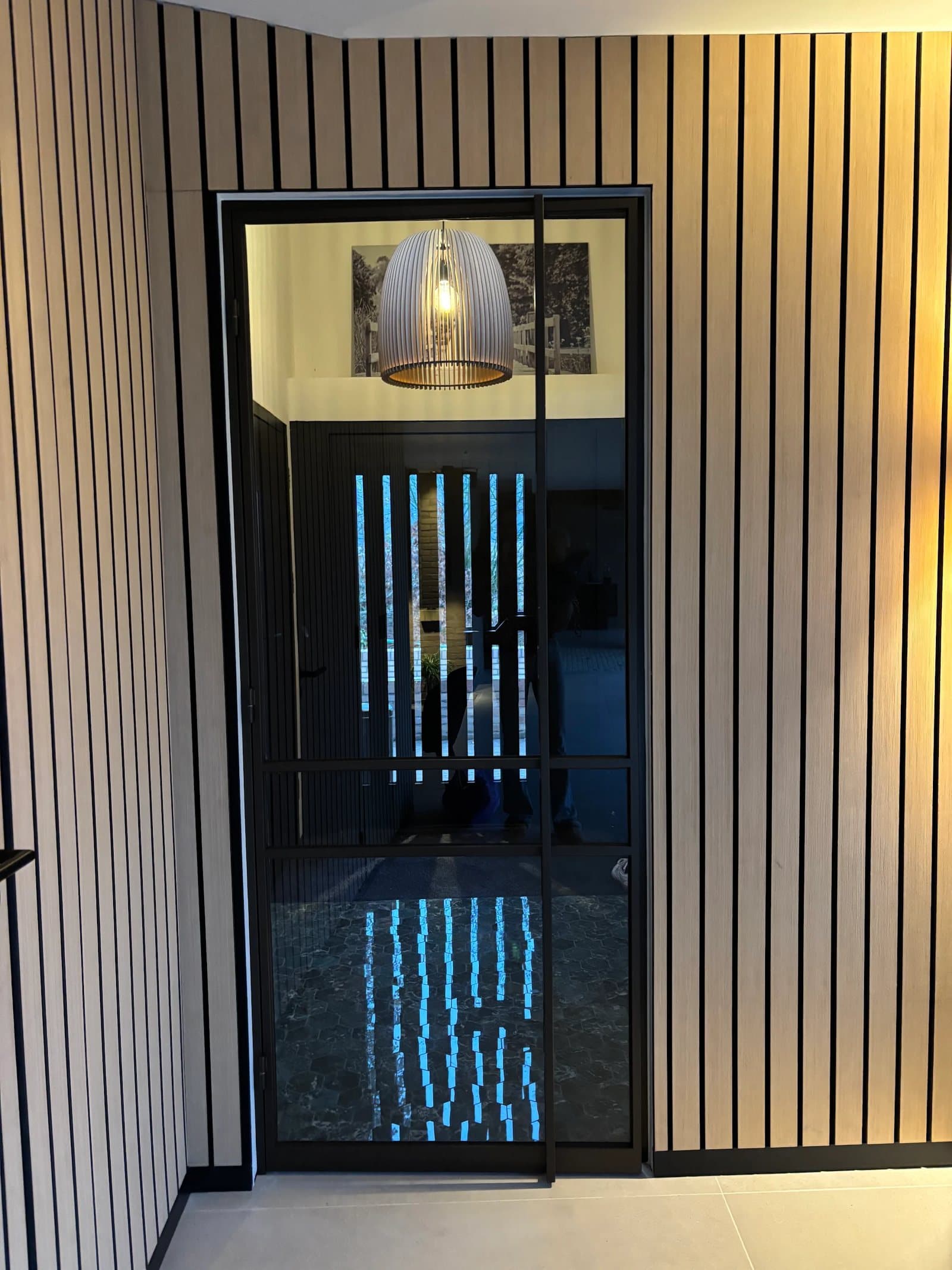 Stalen glazen binnendeur in maatwerk wandbekleding van houten lamellen in de gerenoveerde Van Zantinge-villa