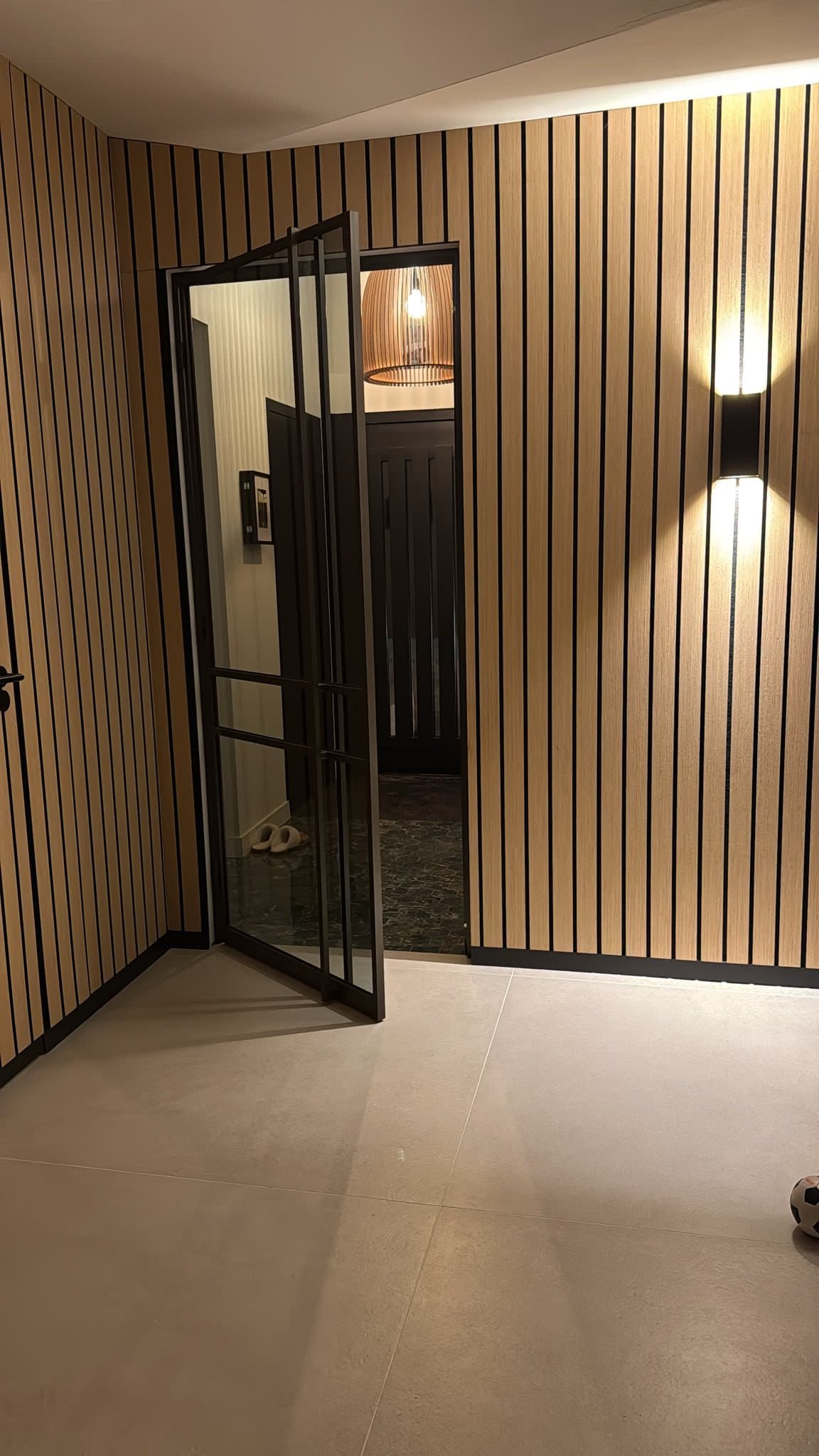 Geopende stalen glazen deur in maatwerk wandbekleding van houten lamellen