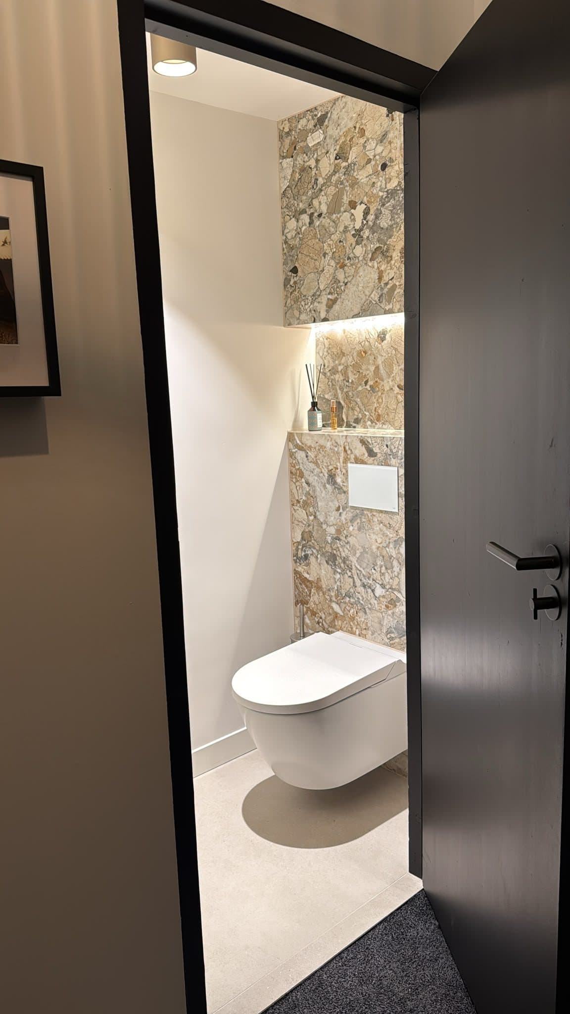 Nieuw toilet met natuursteenlook tegelwerk, verlichte nis en hangend toilet in een Van Zantinge-villa