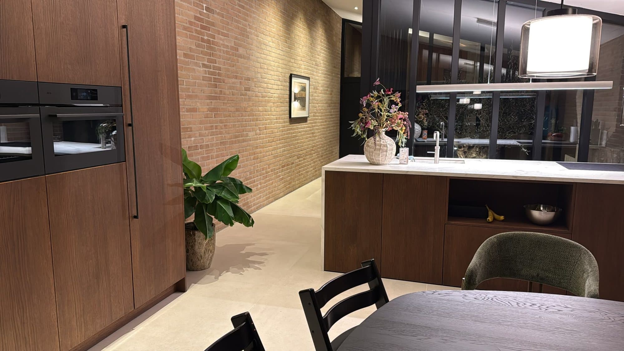 Kookeiland met marmerlook blad, baksteenwand en nieuw lichtplan in de gerenoveerde Van Zantinge-villa