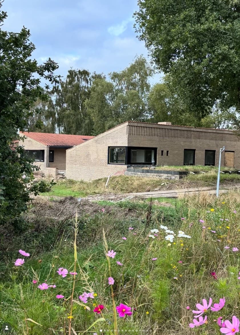 Buitenkant van de gerenoveerde Van Zantinge-bungalow in Enschede met gele baksteen, rode dakpannen en nieuwe zwarte kozijnen