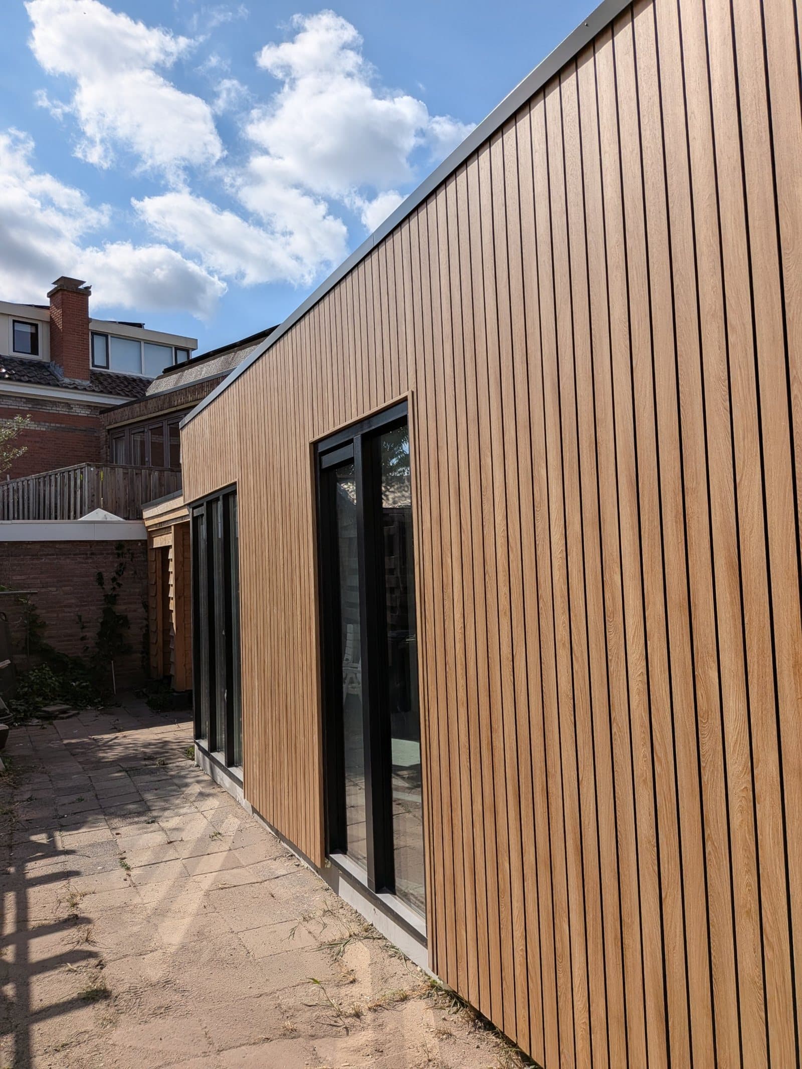 Nieuwe uitbouw in houtskeletbouw met Finiplus gevelbekleding in eikenlook en zwarte kozijnen in Enschede