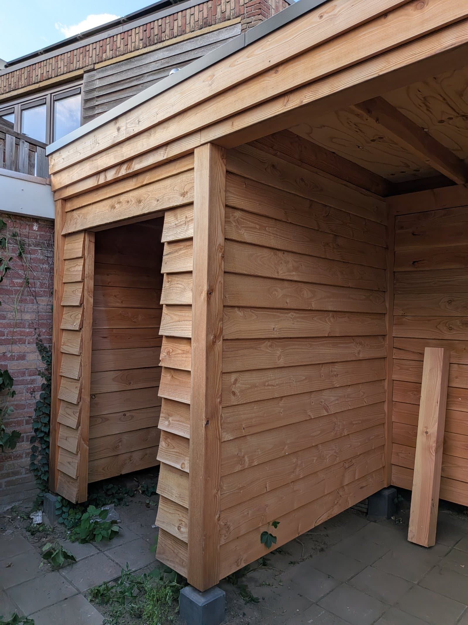 Nieuwe houten overkapping met schuur bij een uitbouw in Enschede