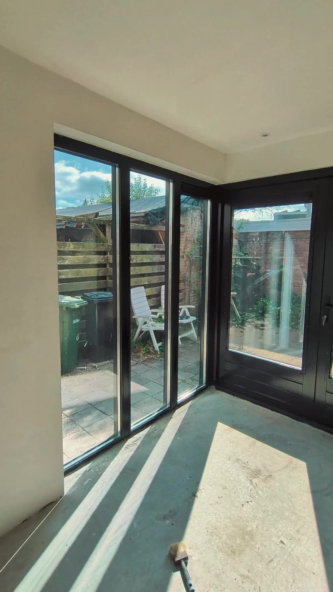 Lichte nieuwe kamer in de uitbouw met grote glazen pui naar de tuin in Enschede